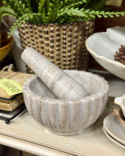 Mortar and pestle set on a shelf with decorative items