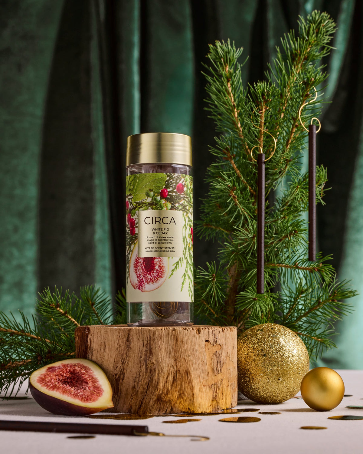 White Fig & Cedar Tree Scent Stems displayed on a small Christmas tree beside their botanical storage tube.