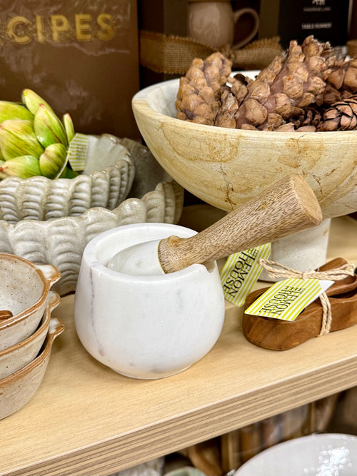 White marble mortar and pestle with wooden handle, angled view
